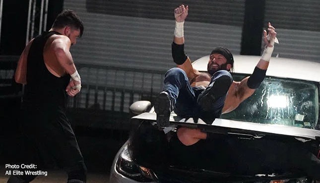Trent being thrown into a car windshield as Chuck Taylor runs to his aid